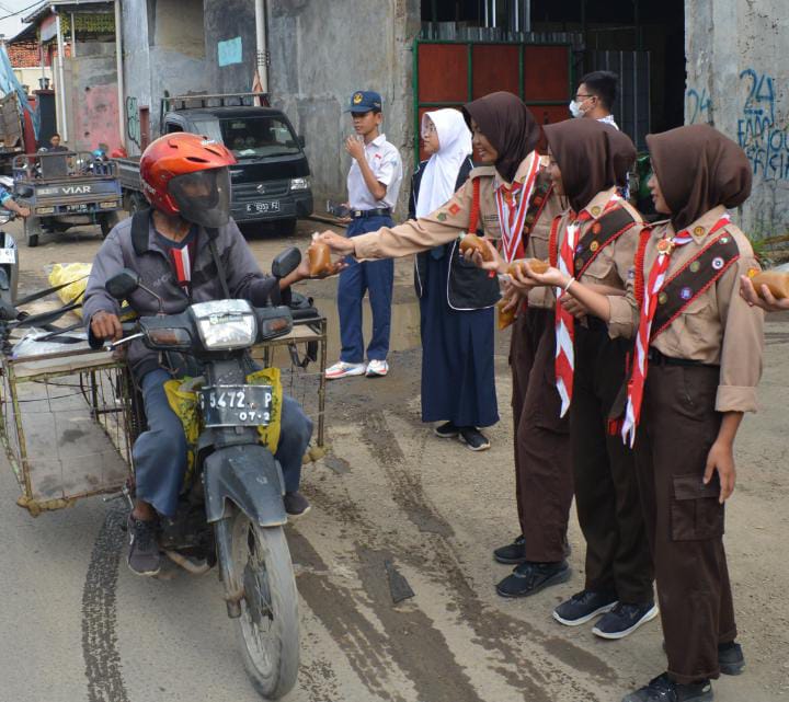 Anggota Pramuka dan OSIS SMP N 1 Talang membagikan takjil kepada pengendara